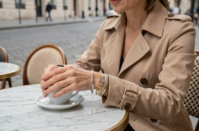 Femme élégante en terrasse de café parisien avec des bracelets tendance empilés Etam en argent et or